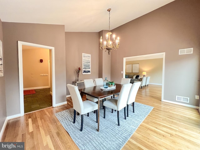 dining room featuring light wood-type flooring, visible vents, baseboards, and a notable chandelier