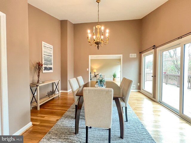 dining area featuring an inviting chandelier, light wood-style flooring, baseboards, and visible vents