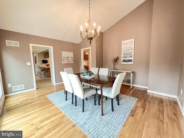 dining room featuring visible vents, light wood-style flooring, and vaulted ceiling