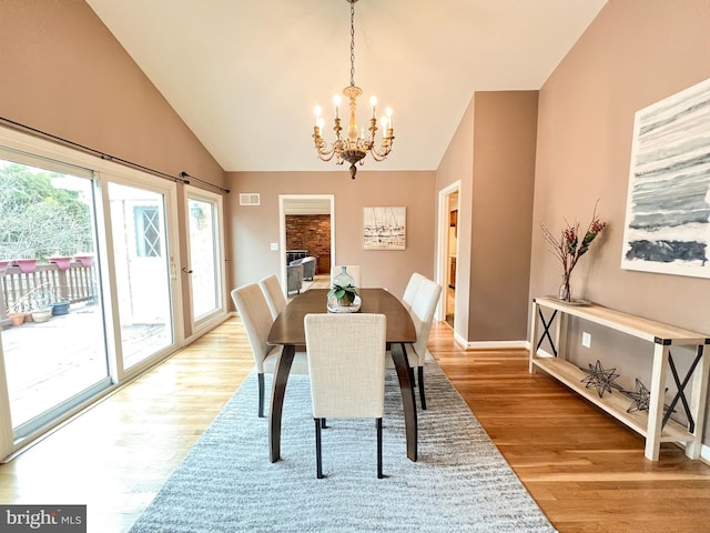 dining area featuring vaulted ceiling, a notable chandelier, visible vents, and light wood-type flooring