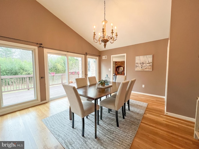 dining space featuring a notable chandelier, plenty of natural light, light wood-style flooring, and high vaulted ceiling