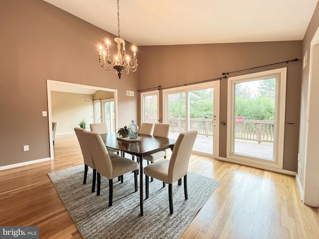 dining space featuring light wood-type flooring, visible vents, a notable chandelier, high vaulted ceiling, and baseboards