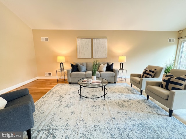 living area with wood finished floors, visible vents, and baseboards