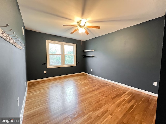 empty room with ceiling fan, baseboards, and wood finished floors