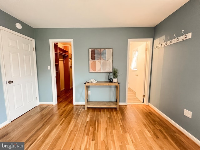 interior space featuring a walk in closet, light wood-style floors, baseboards, and a closet