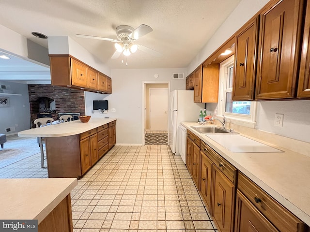 kitchen with a sink, visible vents, brown cabinets, and light countertops