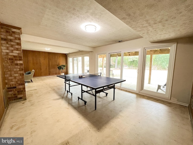 playroom with visible vents, wood walls, and a textured ceiling