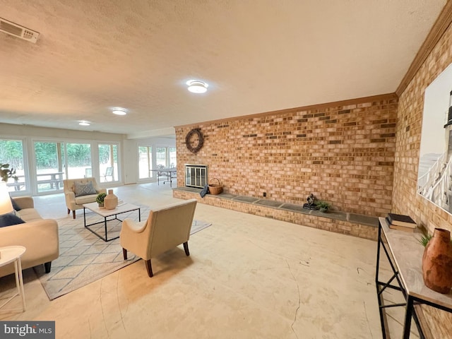 living area with a brick fireplace, visible vents, brick wall, and a textured ceiling