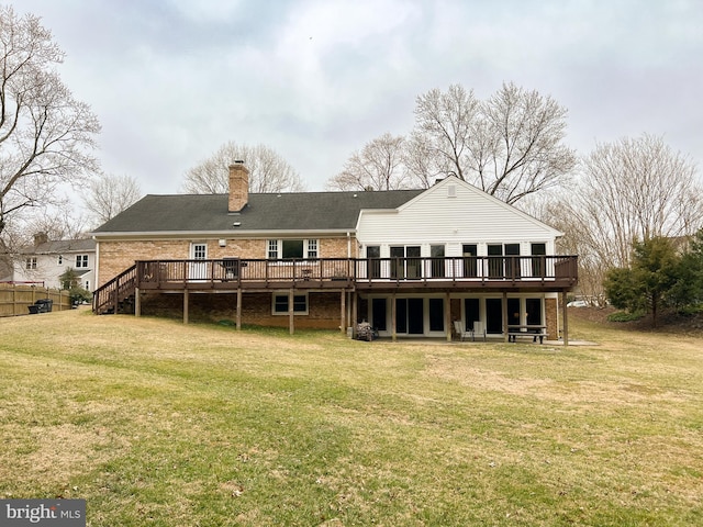 rear view of property featuring a yard, brick siding, a deck, and a chimney