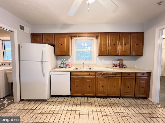 kitchen featuring white appliances, visible vents, washer / dryer, light countertops, and brown cabinets