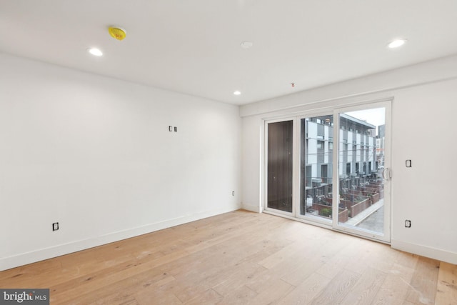 spare room featuring light wood finished floors, recessed lighting, and baseboards