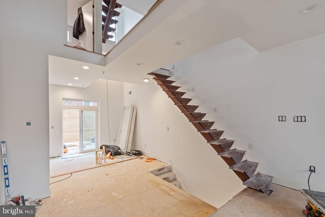 stairs with a high ceiling, recessed lighting, and baseboards