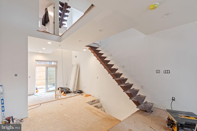 staircase featuring recessed lighting and a towering ceiling