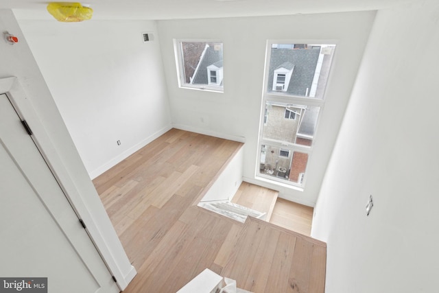 interior space featuring a wealth of natural light, visible vents, baseboards, and wood finished floors