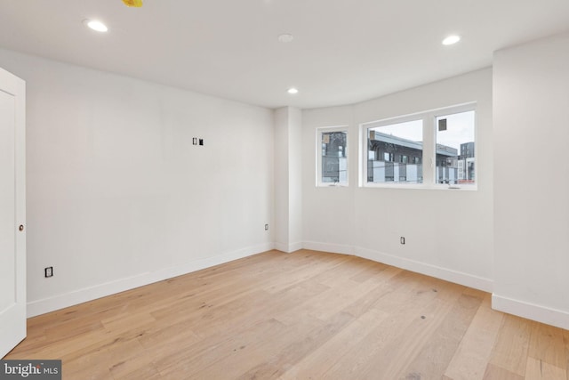 spare room featuring light wood finished floors, recessed lighting, and baseboards