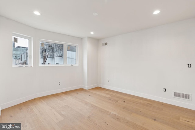 spare room with light wood-style floors, visible vents, and a healthy amount of sunlight