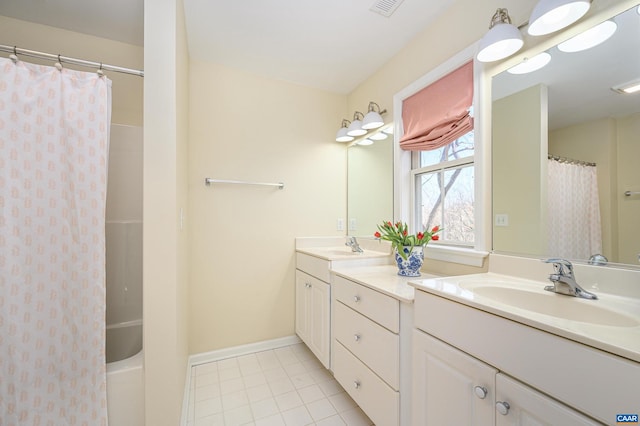 bathroom featuring double vanity, tile patterned flooring, a sink, and baseboards