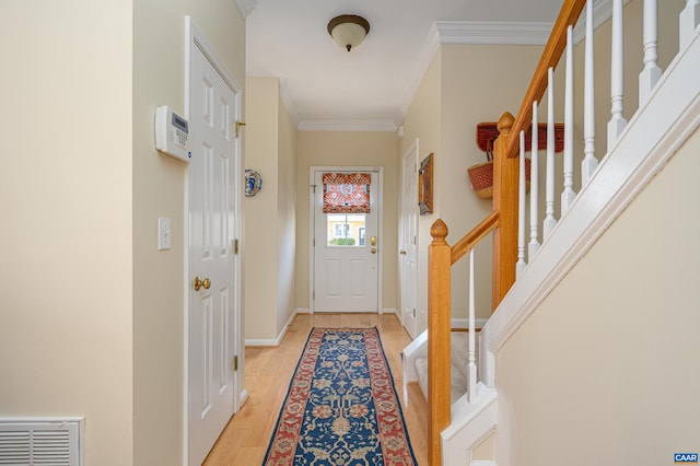 doorway with visible vents, baseboards, light wood-style floors, ornamental molding, and stairway