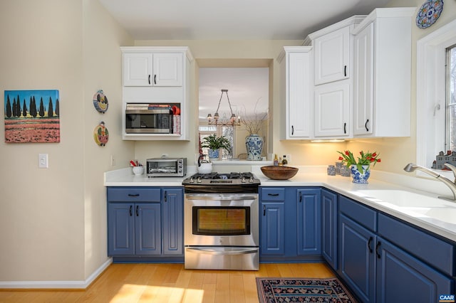 kitchen featuring blue cabinets, light wood finished floors, appliances with stainless steel finishes, and white cabinets