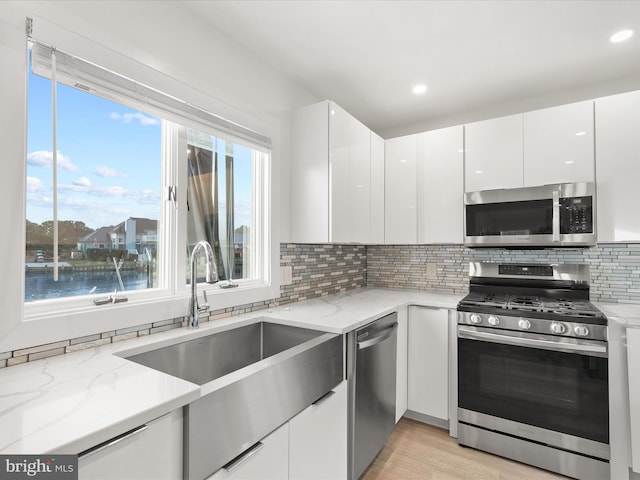 kitchen with stainless steel appliances, white cabinetry, a sink, and modern cabinets