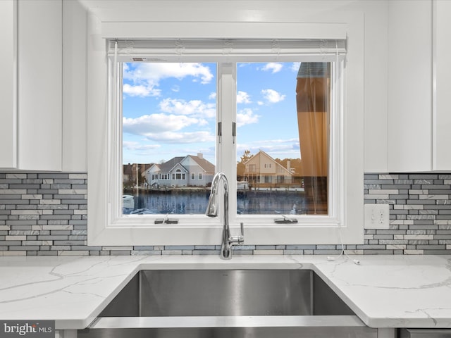 kitchen with white cabinetry, a sink, and backsplash