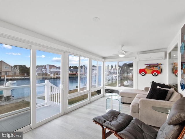 sunroom with a ceiling fan, a water view, and a wall mounted AC