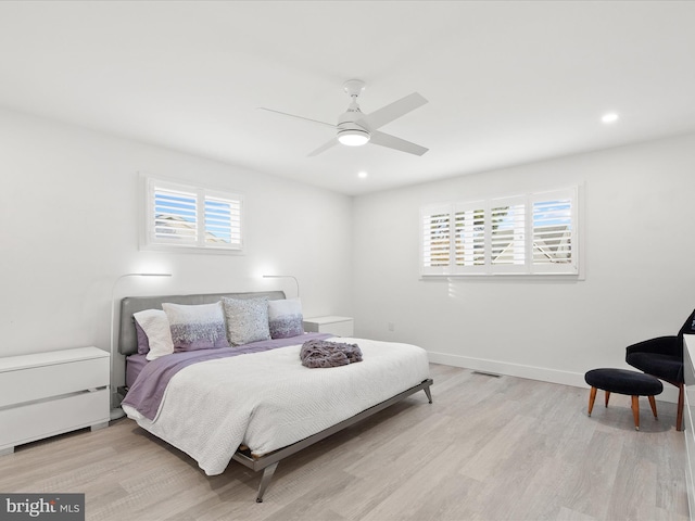 bedroom featuring baseboards, multiple windows, and light wood finished floors