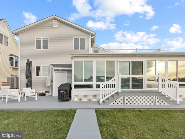 rear view of property with entry steps, a sunroom, a patio area, and a lawn