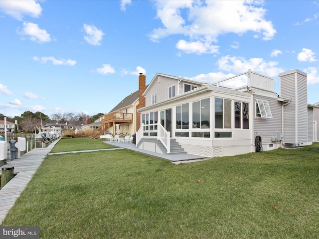 rear view of house with a yard, a chimney, and a sunroom