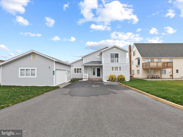 view of front of property featuring aphalt driveway, a balcony, and a front lawn