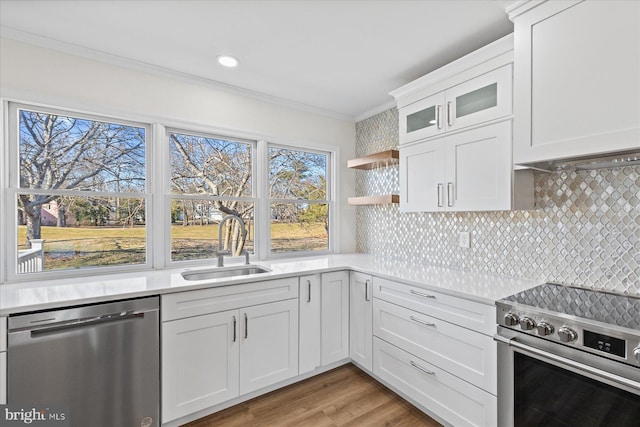 kitchen featuring white cabinets, appliances with stainless steel finishes, ornamental molding, light countertops, and a sink