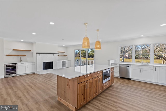 kitchen with wine cooler, light wood-style flooring, appliances with stainless steel finishes, a brick fireplace, and a sink