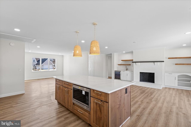 kitchen with wine cooler, light wood finished floors, open shelves, stainless steel microwave, and open floor plan