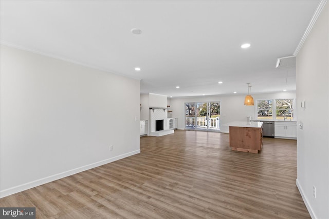 unfurnished living room featuring crown molding, baseboards, a fireplace with raised hearth, and wood finished floors