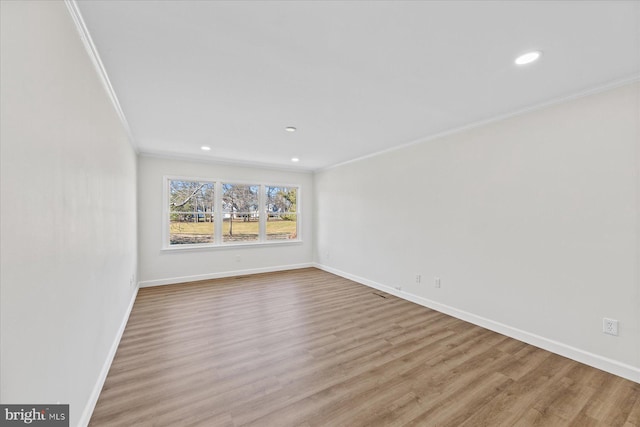 spare room with ornamental molding, baseboards, and wood finished floors