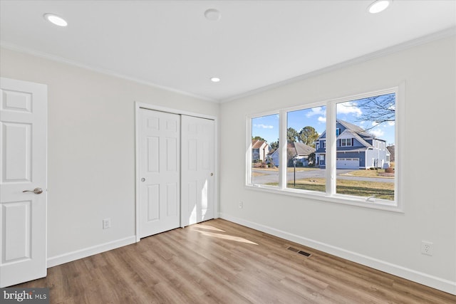 unfurnished bedroom featuring baseboards, visible vents, wood finished floors, and ornamental molding