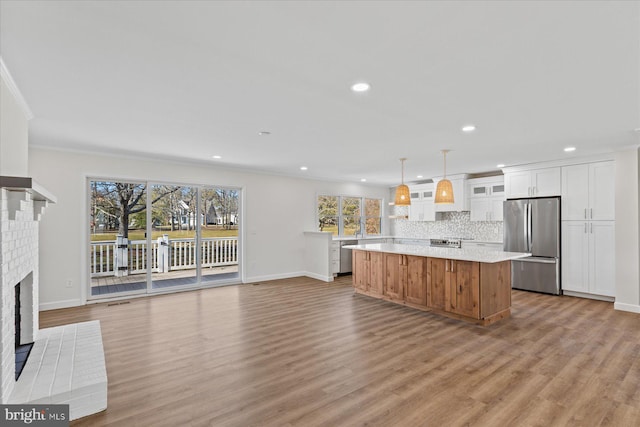 kitchen featuring a center island, stainless steel appliances, light countertops, backsplash, and white cabinetry