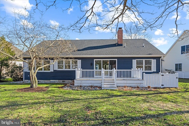 rear view of property with a wooden deck, a chimney, roof with shingles, and a yard