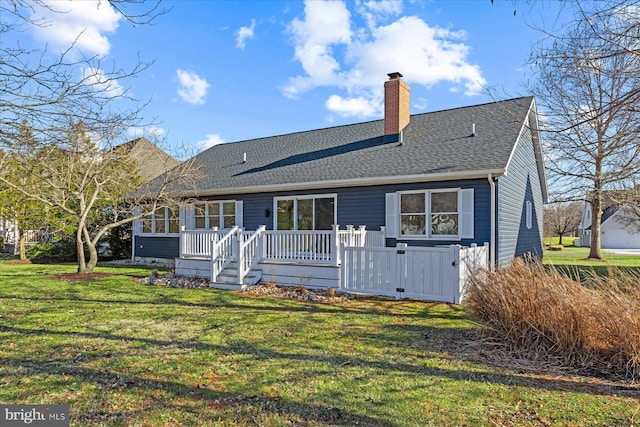 rear view of property featuring a deck, a yard, a shingled roof, and a chimney