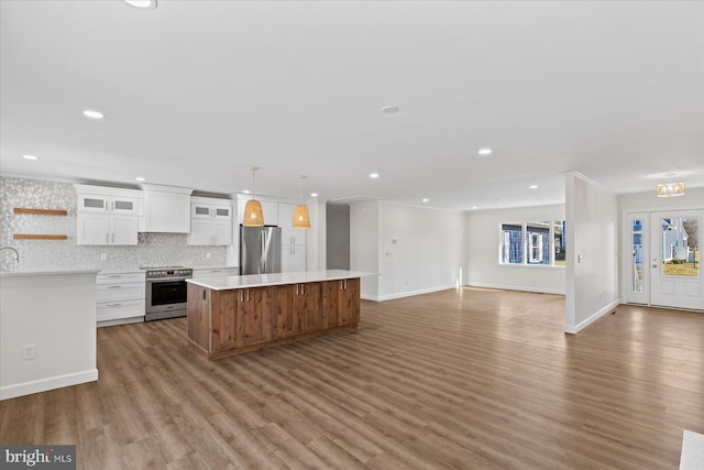 kitchen with light wood finished floors, light countertops, appliances with stainless steel finishes, white cabinets, and a kitchen island