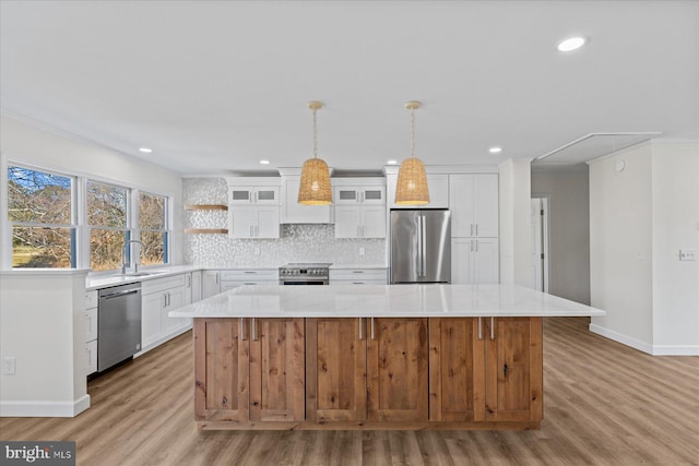 kitchen featuring ornamental molding, appliances with stainless steel finishes, a center island, light countertops, and backsplash