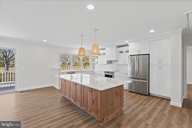 kitchen with a healthy amount of sunlight, appliances with stainless steel finishes, decorative backsplash, and light countertops