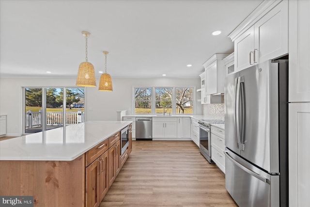 kitchen with light wood-type flooring, a kitchen island, appliances with stainless steel finishes, and white cabinets