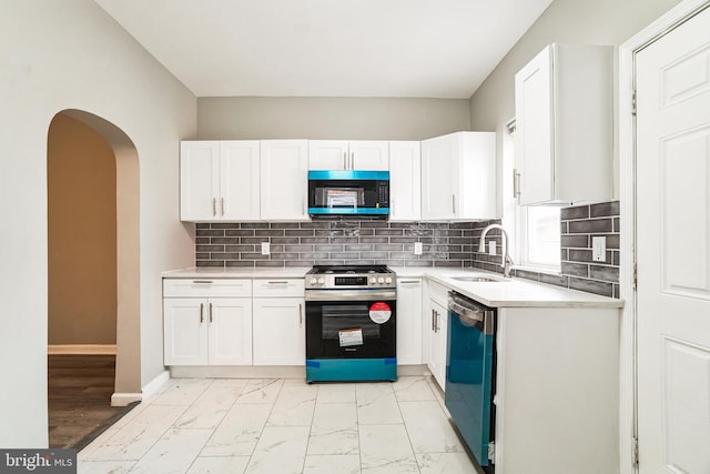 5717 Addison St, Philadelphia, PA 19143 - kitchen featuring stainless steel gas stove, dishwasher, a sink, light marble finish floors, and white cabinets