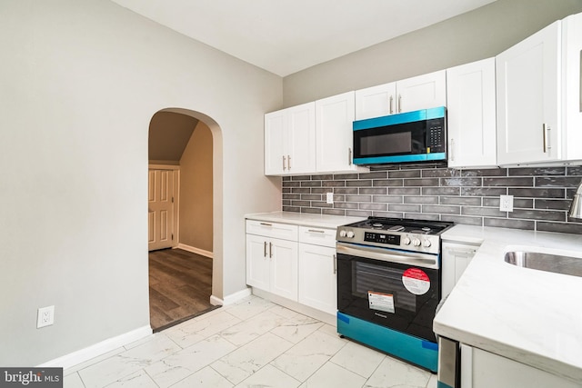 5717 Addison St, Philadelphia, PA 19143 - kitchen featuring stainless steel stove, light marble finish flooring, arched walkways, light countertops, and baseboards