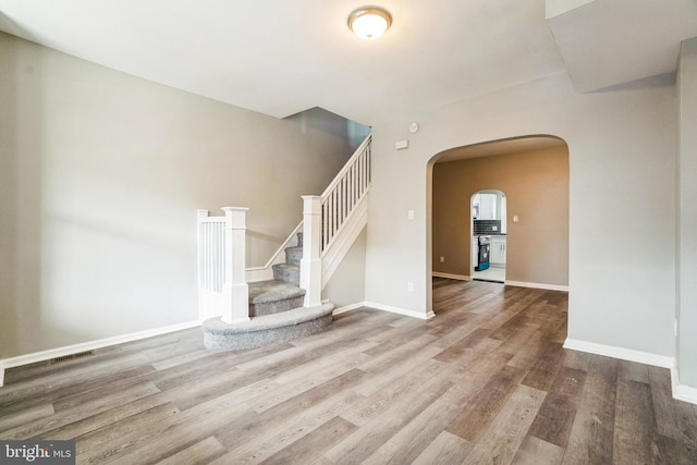 5717 Addison St, Philadelphia, PA 19143 - unfurnished living room with arched walkways, wood finished floors, stairs, and baseboards