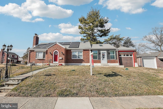 single story home featuring brick siding, solar panels, an attached garage, a front yard, and fence