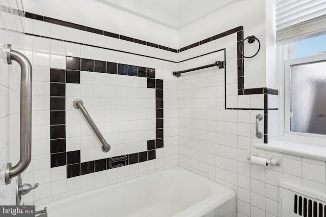 bathroom with shower / bathing tub combination, tile walls, and radiator heating unit