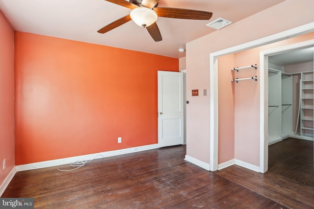 unfurnished bedroom with baseboards, visible vents, dark wood finished floors, a spacious closet, and a closet