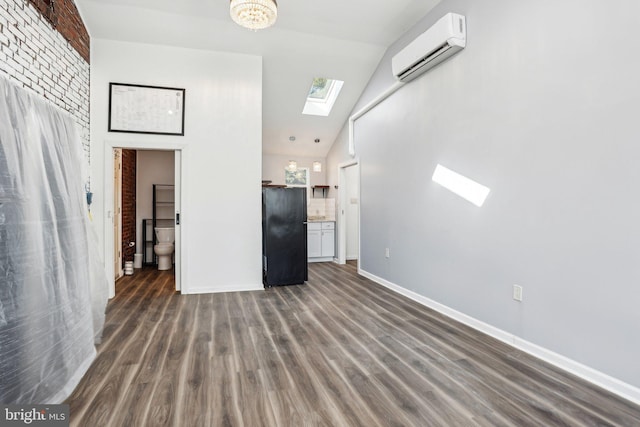 unfurnished living room with vaulted ceiling with skylight, dark wood-type flooring, a wall mounted AC, and baseboards